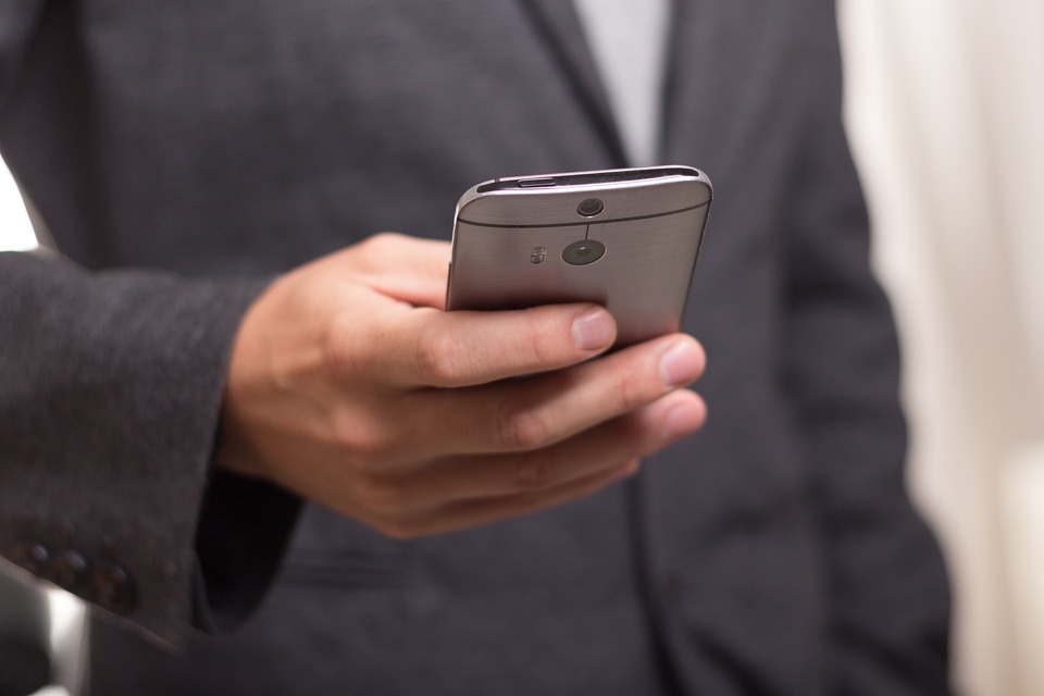 Realtor holding a business phone to cold call their clients